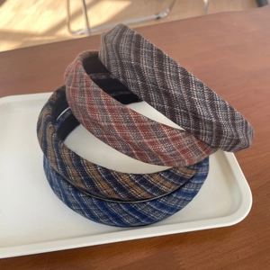 Détail de trois serre-têtes à carreaux épais en tissu sergé gris, rouge foncé et bleu marine