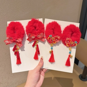 Detail van rode pluchen haarelastiekjes met Chinees borduursel, bellen en kwastjes
