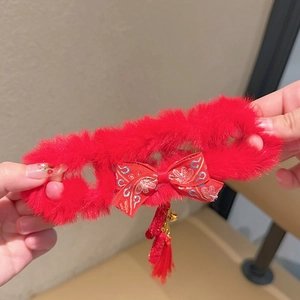 Detail van rood pluche haaraccessoire met Chinese knoop, belletje en lange franje kwast