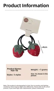 Détail de l'élastique à cheveux fraise tricoté rouge avec feuilles vertes sur carte
