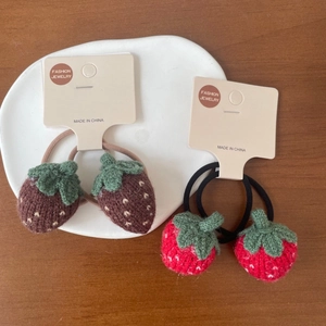 Détail de chouchous fraises en laine faits main présentés sur une assiette en céramique