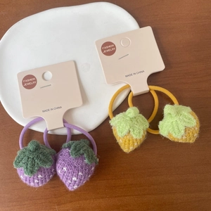 Détail de chouchous fraises au crochet faits main en jaune et violet sur plateau céramique