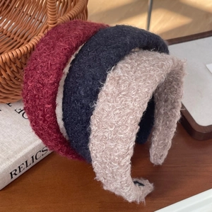 Detail van dikke haarbanden van wolmix in de kleuren bordeauxrood, donkerblauw en beige