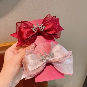 Détail de nœuds à cheveux rouges et roses avec couronnes en strass sur carte