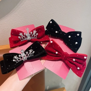 Détail de pinces à cheveux noeud en velours rouge et noir avec perles et couronnes