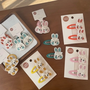 Vue détaillée de barrettes et chouchous lapin tricotés main sur plateau bois