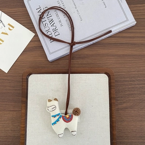 Detail of handcrafted embroidered alpaca charm with colorful saddle on a wooden tray