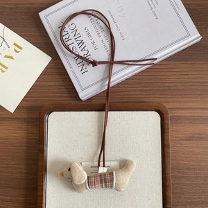 Detail of dachshund plush pendant with pink plaid outfit on a vintage wooden display