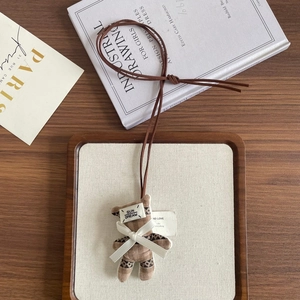 Detailed view of check pattern plush bear pendant with SUN DREAM label and bow