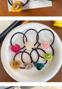Detailed top view of 8 colorful resin rose hair ties arranged on a white ceramic plate