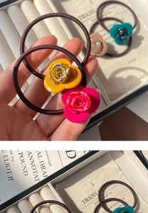 Detailed close-up of colorful resin flower hair ties in an elegant jewelry box