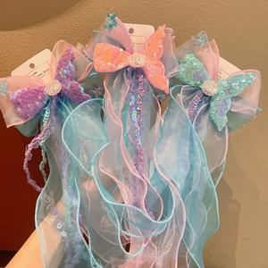 Detail of glittery mermaid tail bow hair clips with sequins and long colorful ribbons