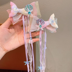 Detail of mermaid hair clips with iridescent organza bows and seashell pendants