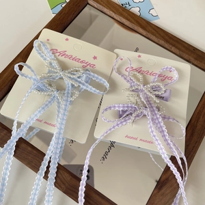 Detail of handmade pearl bow hair clips with pastel blue and purple checkered patterns