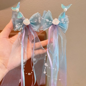 Detail of mermaid hair clip with iridescent sequin tail, mesh bow and pearl tassel