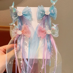 Close-up of mermaid tail hair clips with long mesh tassels and iridescent shell details