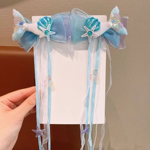Detail of mermaid bow hair clips with long tassels, sea shells, and colorful ribbons