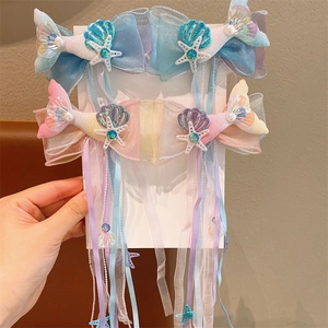 Sparkling mermaid tail hair clips with long ribbons and pearls on a white display card