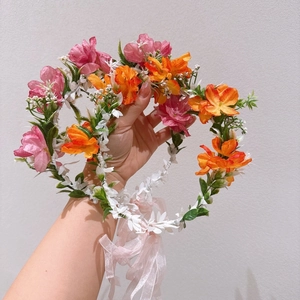 Détail d'un serre-tête floral fait main avec fleurs artificielles roses, oranges et rubans