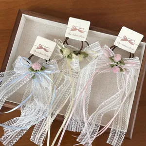 Detalle de coleteros de encaje con cintas largas en tonos azul, beige y rosa suave