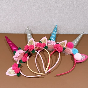Close-up of four colorful sequined unicorn headbands with soft fabric flowers and pom-poms