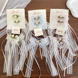 Detalle de los lazos de encaje para el pelo con cintas de seda y pequeñas rosas de mano