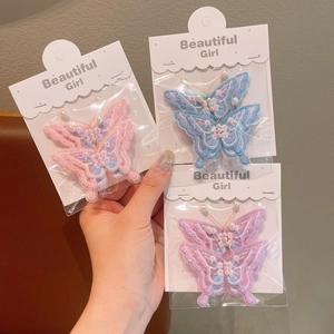 Détail de pinces à cheveux papillon brodées avec perles en rose, bleu et violet