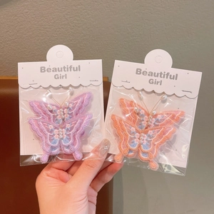 Détail de barrettes papillons brodées avec perles synthétiques sur cartes de support