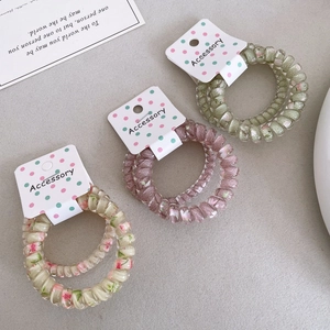 Detailansicht der Spiral-Haargummis mit Blumenmuster und einfarbigem lila Design