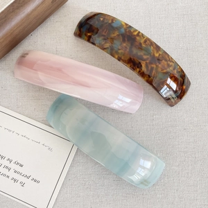 Detailed close-up of three acetate hair clips with amber and marble patterns
