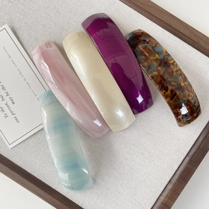 Detail of colorful curved acetate hair clips with France Handmade text on beige fabric