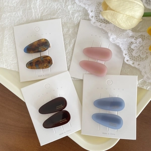 Detail view of colorful water-drop hair clips on cardboards with floral background