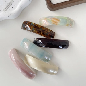 Set of 6 colorful acetate hair clips in tortoiseshell and marble patterns on white surface