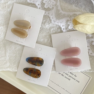 Detail showing set of six oval matte hair clips in beige and amber on white lace