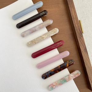 Macro detail of eight colorful acetate hair clips with gold Borrette La France lettering