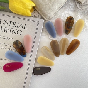 Detailed set of eleven colorful handmade acetate teardrop hair clips on vintage background