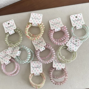 Nahaufnahme bunter Spiral-Haargummis im Set auf minimalistischer Verpackung aus Karton