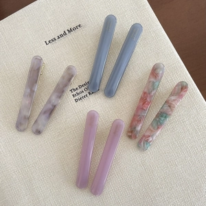Detailed close-up of four pairs of elegant acetate hair clips with marble and floral patterns