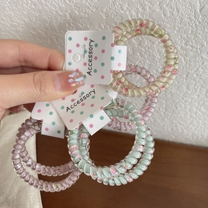 Detail von floralen Spiralhaargummis in Pastelltönen mit dekorativer Verpackung