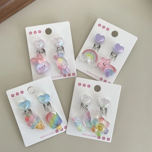 Macro view of colorful resin ear clips for kids featuring heart and rainbow designs