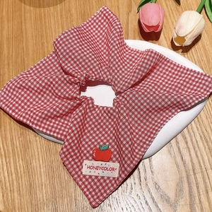 Detailed shot of red plaid oversized scrunchie with apple embroidery on a wooden table