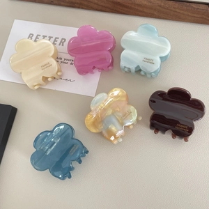 Detail of six colorful floral hair claws in acetate finish on a beige leather background