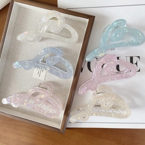 Detail of five colorful heart-shaped hair claws in a wooden tray with pearlescent finish