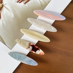 Detail view of five elegant acetate hair clips with marble patterns and glossy finish