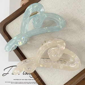 Detail showing heart-shaped hair claws in light blue and beige with pearl finish