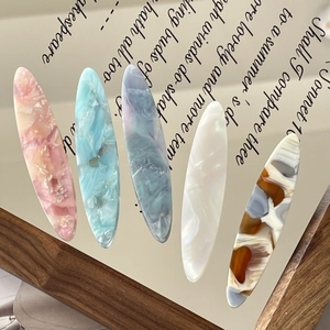 Set of five acetate hair clips in pastel marble colors on a vintage literary background