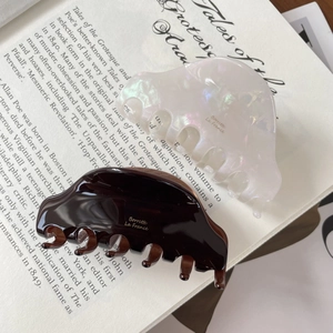French vintage style acetate hair claws in pearl white and dark brown resin on a book