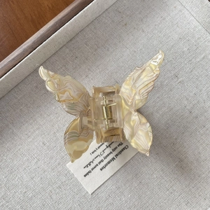 Elegante pinza per capelli a farfalla in acetato con trama marmorea su fondo in lino