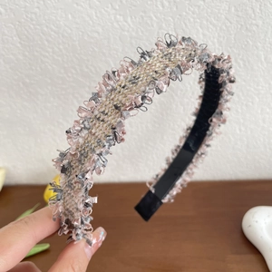 Close-up of pink and grey tweed headband with golden thread and fringed edges