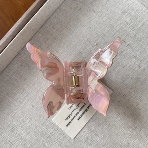 Dettaglio di un fermaglio per capelli a farfalla in acetato rosa marmorizzato con molla
